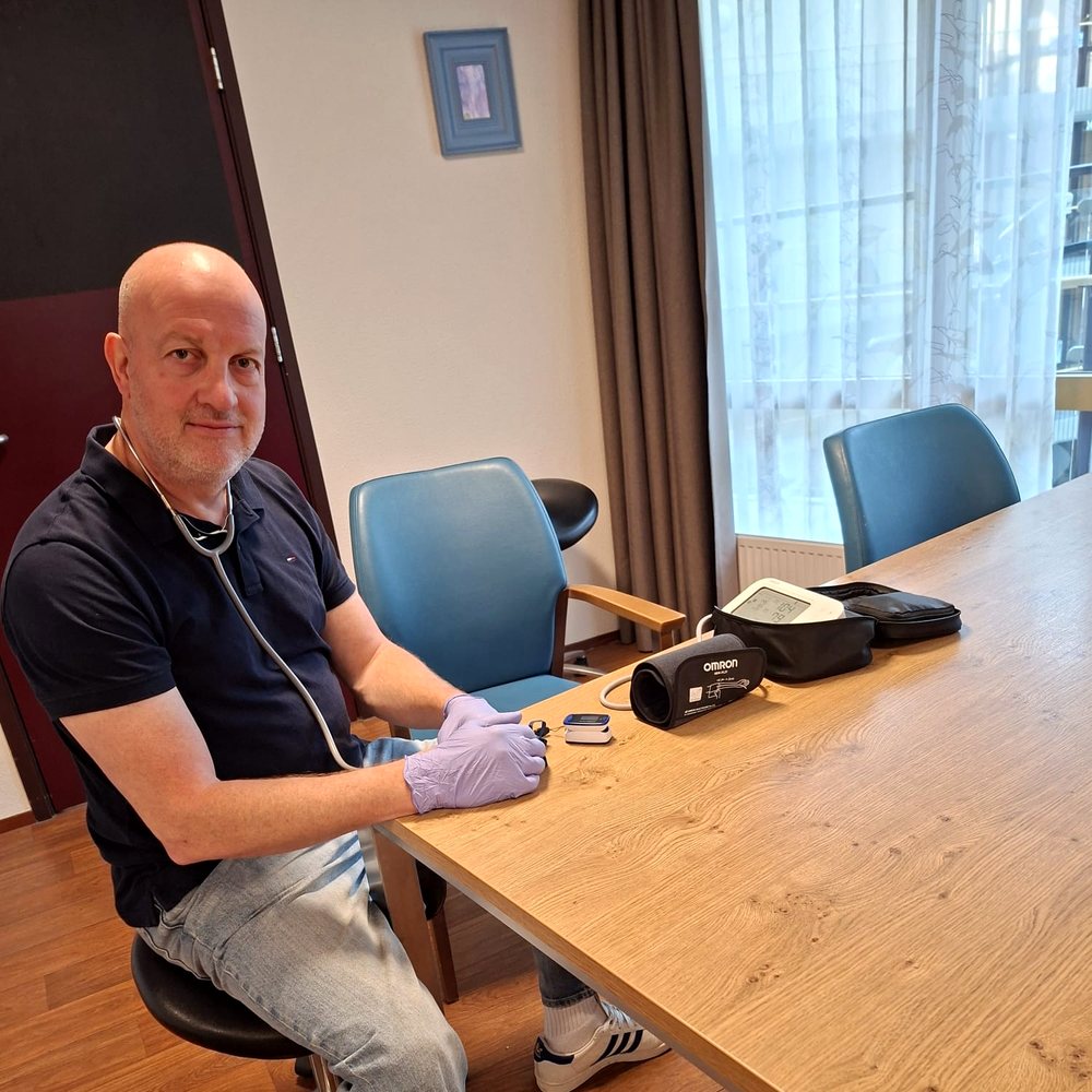 Willem zit aan tafel klaar met zijn bloeddrukmeter en saturatiemeter