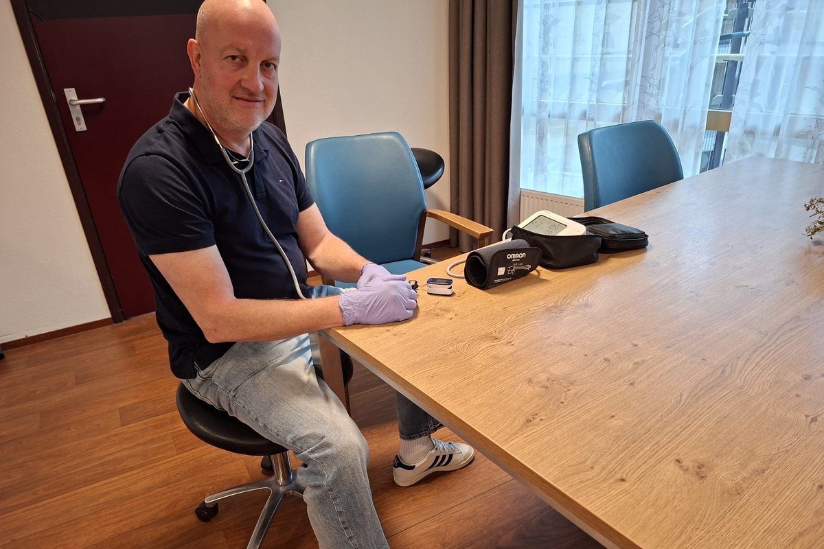 Willem zit klaar aan tafel met zijn meetapparatuur, met een chatbericht van iemand die een check wil plannen